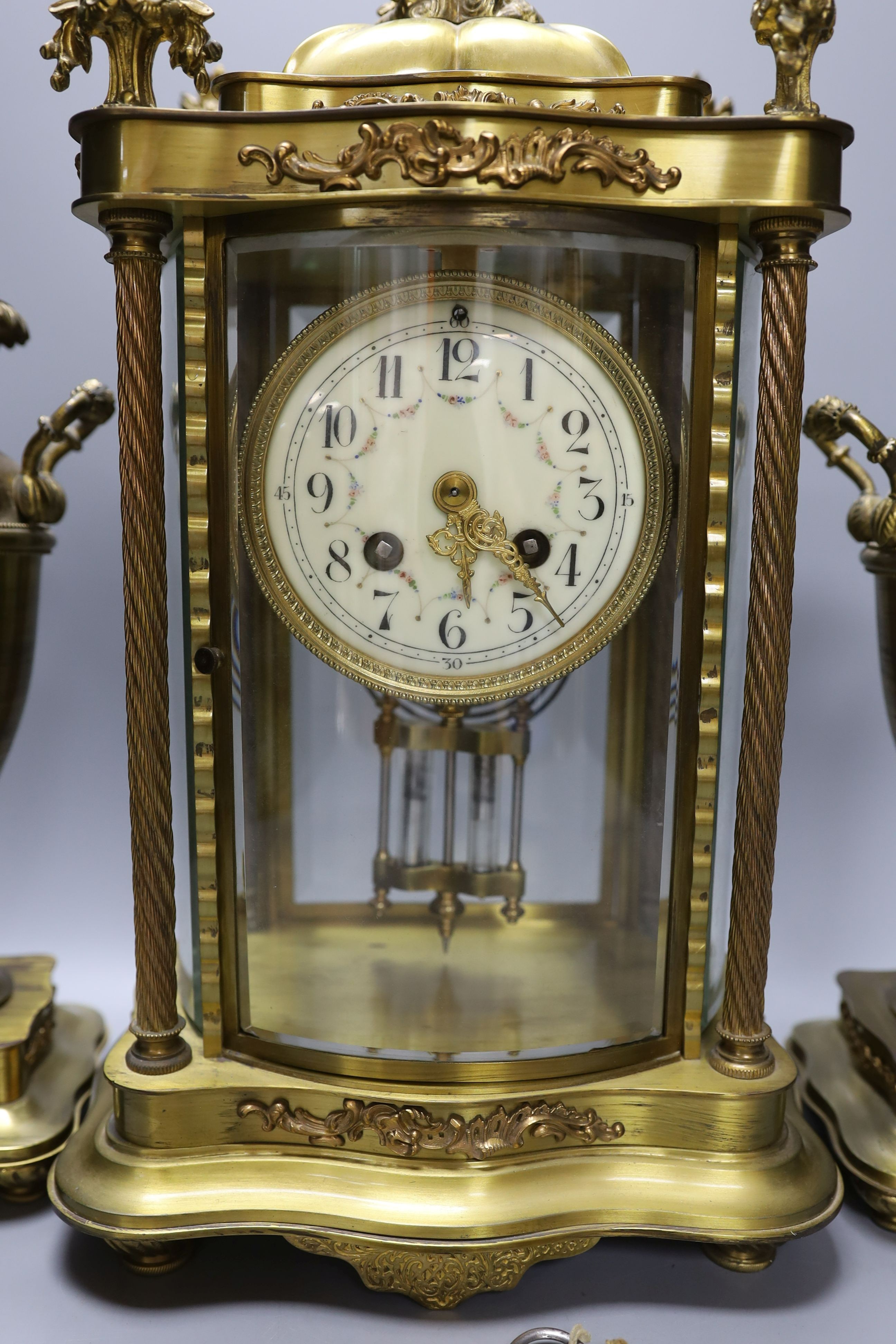 An early 20th century French brass four glass mantel clock garniture with key and pendulum, 41cm tall